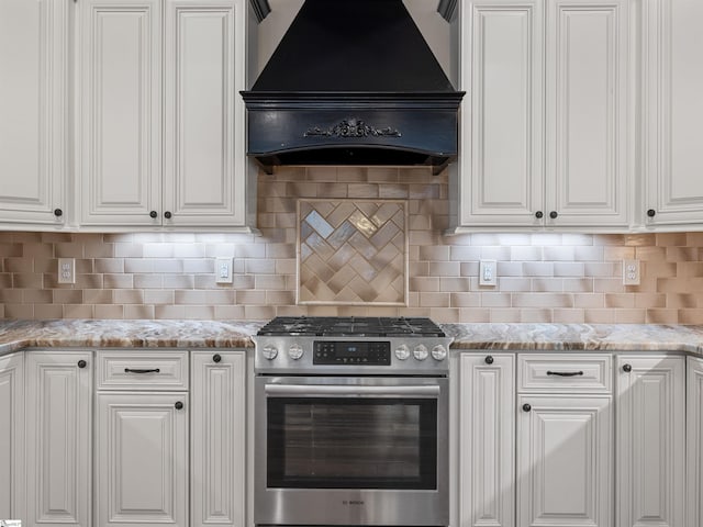 kitchen featuring stainless steel range with gas cooktop, custom range hood, and white cabinetry