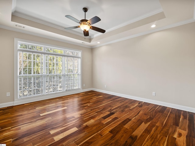 unfurnished room featuring baseboards, visible vents, a tray ceiling, and wood finished floors