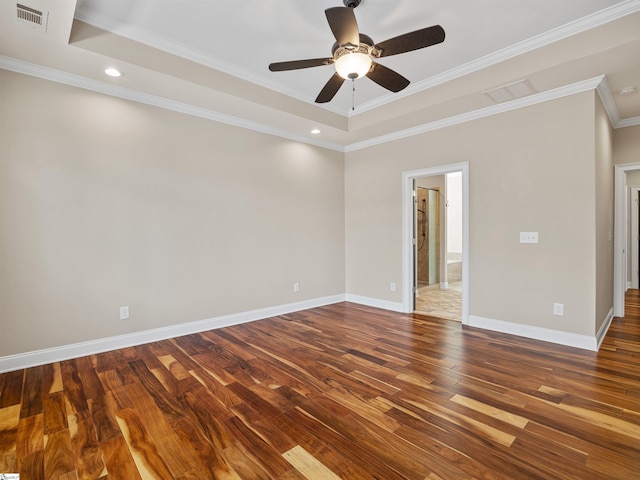 spare room featuring baseboards, visible vents, a raised ceiling, ornamental molding, and wood finished floors