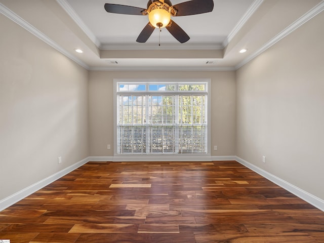 spare room featuring crown molding, baseboards, a raised ceiling, and wood finished floors