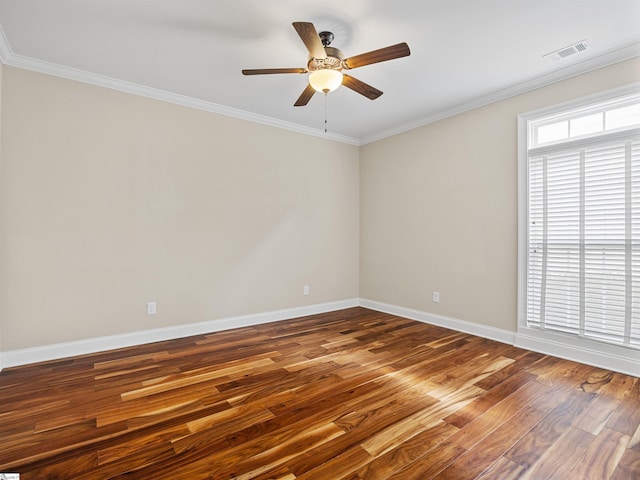 empty room with a healthy amount of sunlight, visible vents, wood finished floors, and ornamental molding