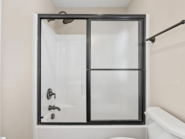 bathroom with shower / bath combination with glass door and toilet