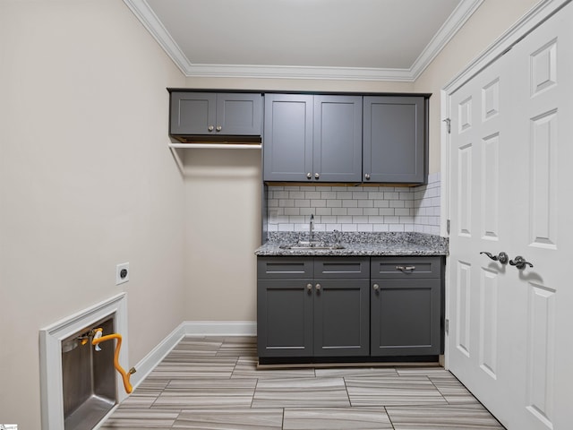 clothes washing area with cabinet space, ornamental molding, hookup for an electric dryer, a sink, and baseboards