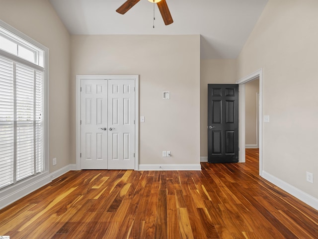 unfurnished bedroom with lofted ceiling, a closet, baseboards, and wood finished floors