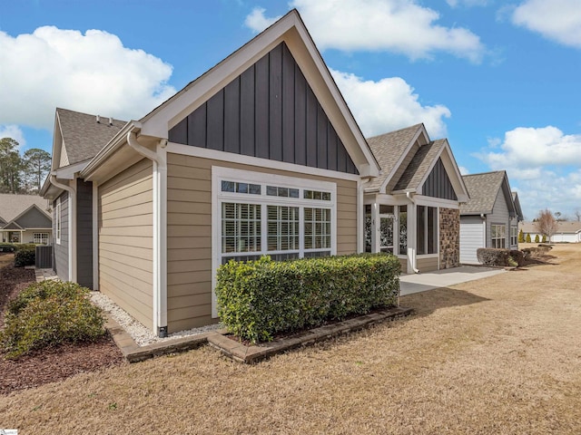 rear view of property with a shingled roof and board and batten siding