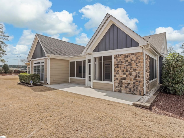 back of house featuring stone siding, a sunroom, board and batten siding, and a patio