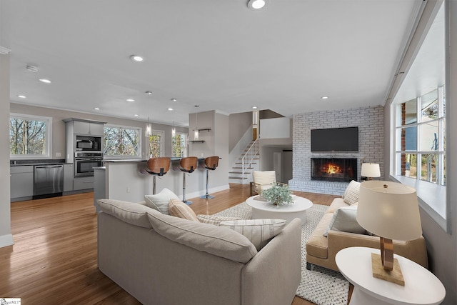 living room with a brick fireplace and light hardwood / wood-style floors