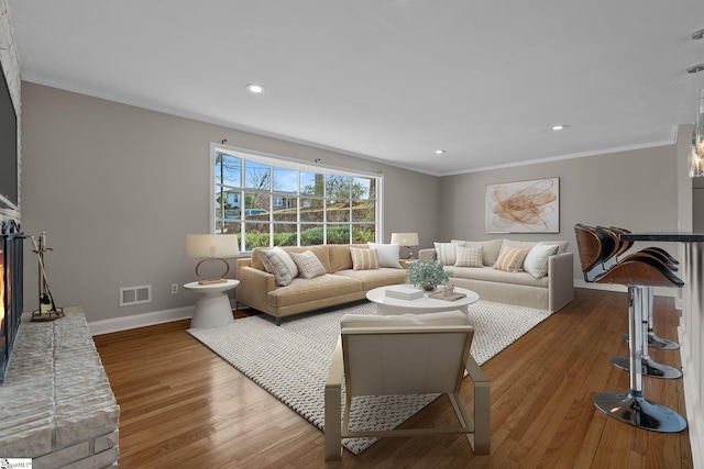 living room with hardwood / wood-style floors, crown molding, and a fireplace