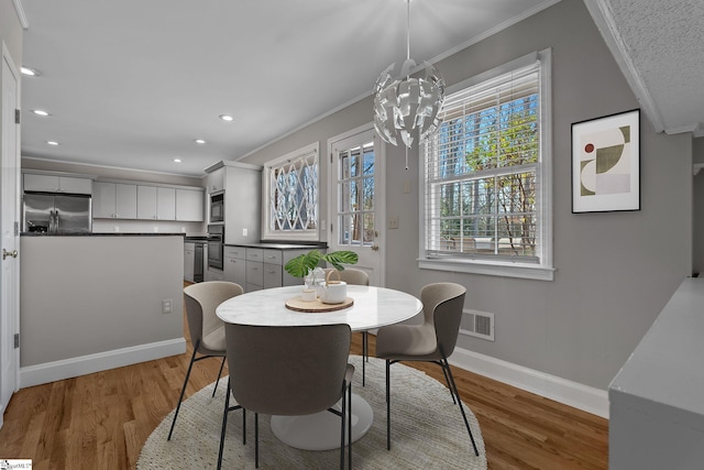 dining space featuring hardwood / wood-style floors, crown molding, and a notable chandelier