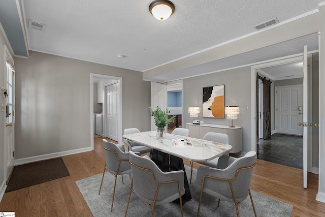 dining space with hardwood / wood-style flooring, crown molding, and a textured ceiling