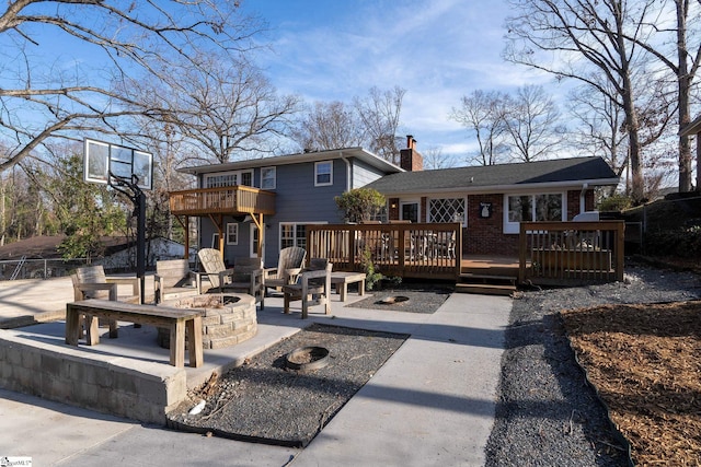 rear view of house featuring a wooden deck and an outdoor fire pit