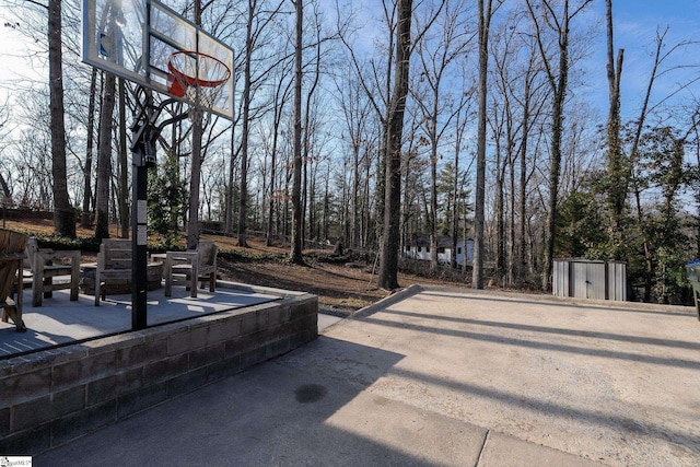 view of patio / terrace featuring basketball hoop and a storage shed