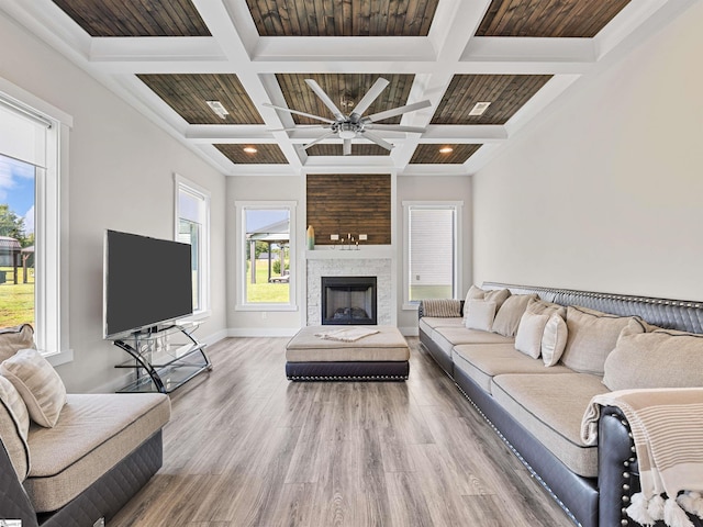 living room with coffered ceiling, wood-type flooring, a large fireplace, ceiling fan, and beam ceiling