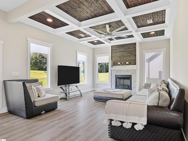 living room featuring beamed ceiling, plenty of natural light, a fireplace, and light wood-type flooring