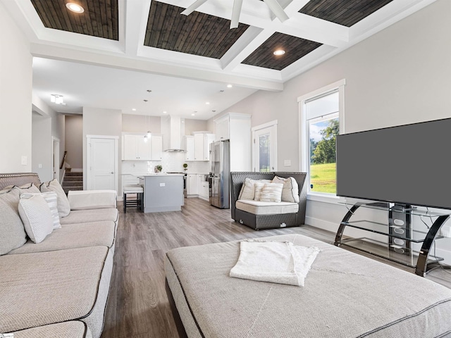 living room with coffered ceiling, beamed ceiling, and light wood-type flooring