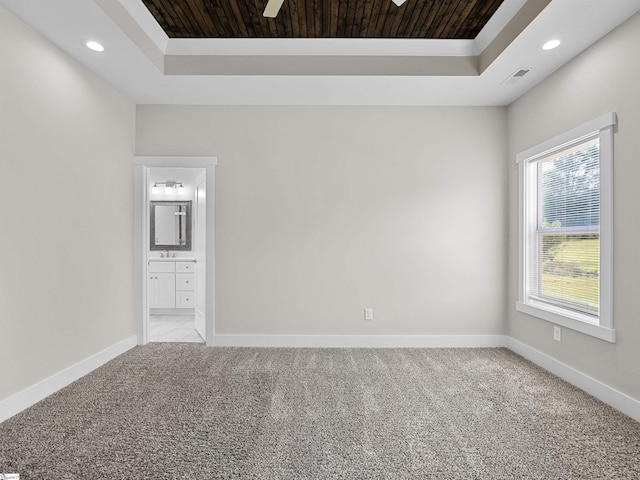 carpeted empty room featuring a tray ceiling and wooden ceiling