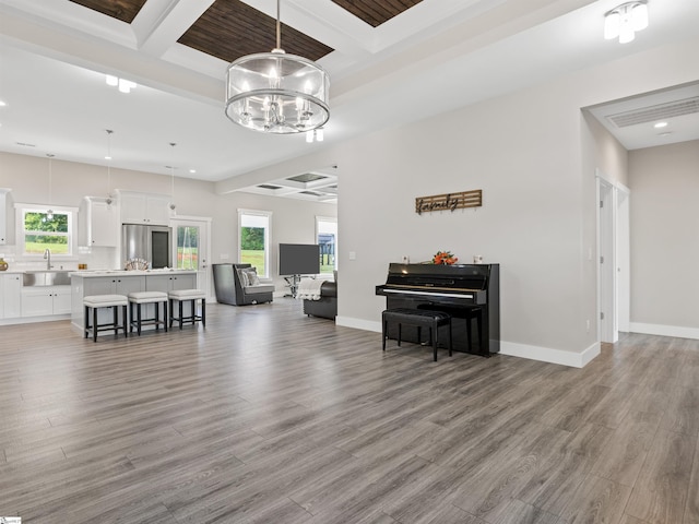 interior space with beamed ceiling, coffered ceiling, sink, and light hardwood / wood-style flooring