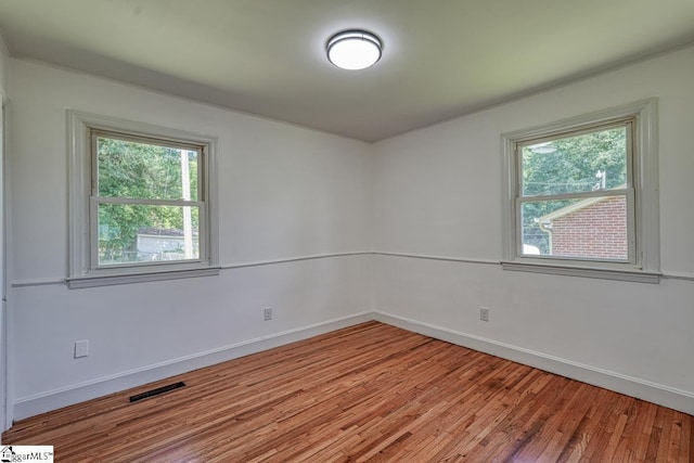 empty room with plenty of natural light and hardwood / wood-style floors