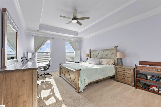 carpeted bedroom with ornamental molding and a tray ceiling