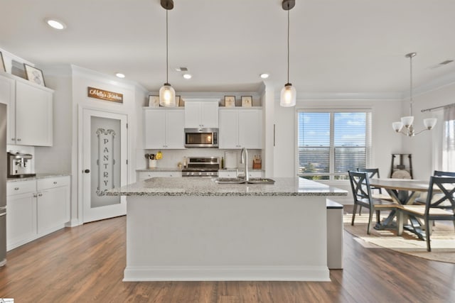 kitchen with stainless steel appliances, an island with sink, and hanging light fixtures