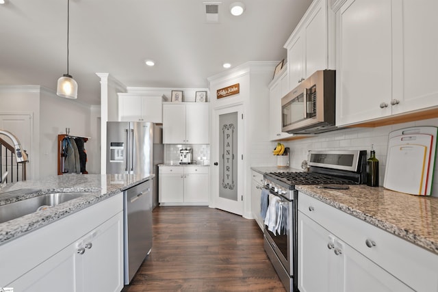 kitchen with pendant lighting, appliances with stainless steel finishes, sink, and white cabinets