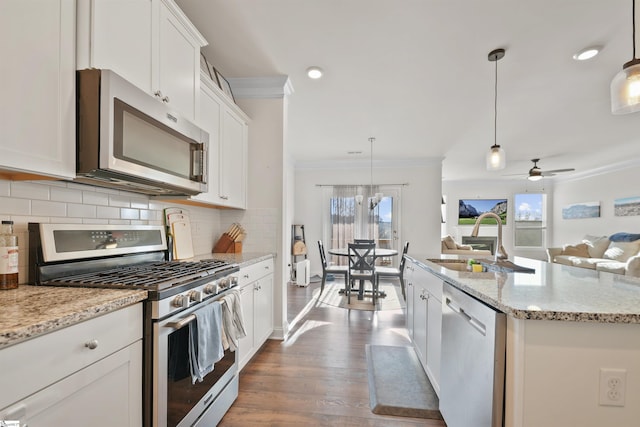 kitchen featuring a kitchen island with sink, sink, decorative light fixtures, and appliances with stainless steel finishes