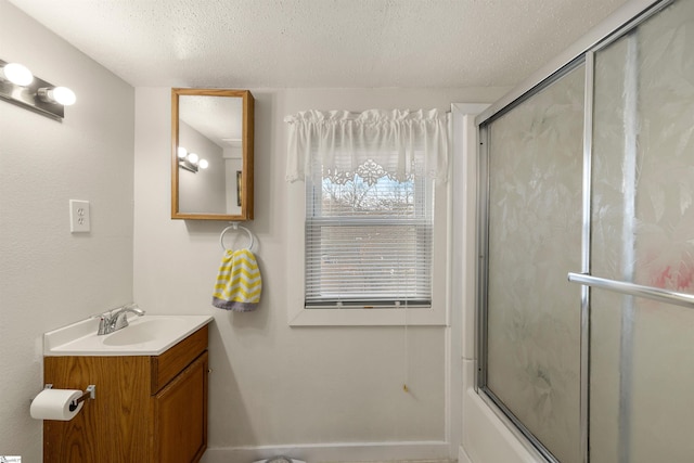 bathroom with vanity, bath / shower combo with glass door, and a textured ceiling