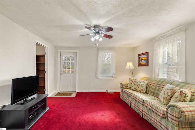 living room with ceiling fan, a textured ceiling, and dark carpet