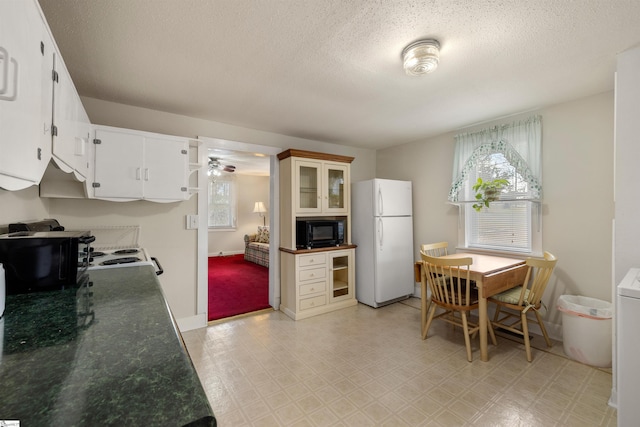 kitchen featuring ceiling fan, a textured ceiling, white cabinets, and white appliances