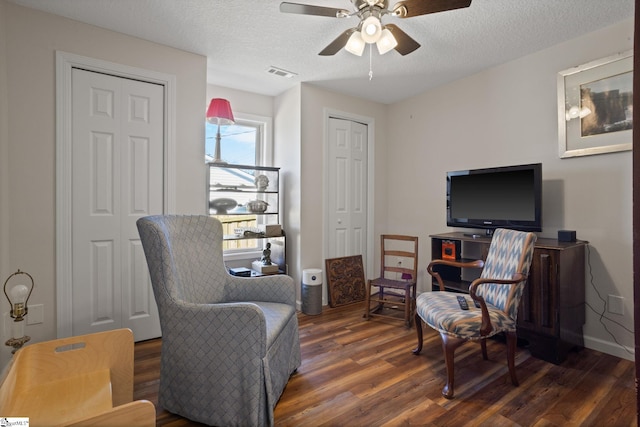 living area featuring ceiling fan, dark hardwood / wood-style floors, and a textured ceiling