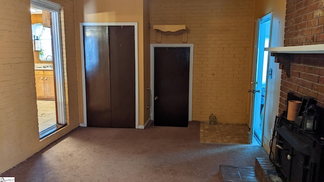 interior space with brick wall, carpet flooring, and a wood stove