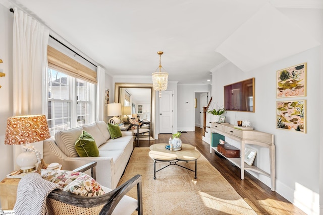 living room with crown molding, wood-type flooring, and an inviting chandelier