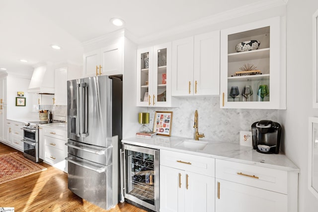 kitchen with premium range hood, sink, appliances with stainless steel finishes, beverage cooler, and white cabinets