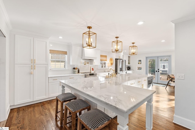 kitchen featuring white cabinetry, a spacious island, appliances with stainless steel finishes, and pendant lighting