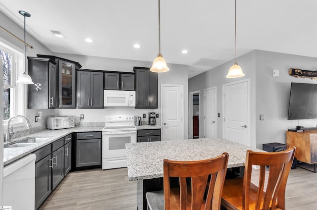 kitchen featuring sink, a kitchen breakfast bar, decorative backsplash, hanging light fixtures, and white appliances