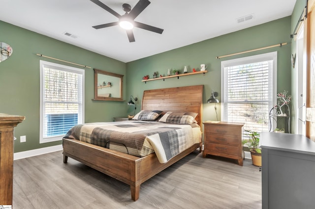 bedroom with ceiling fan, multiple windows, and light wood-type flooring