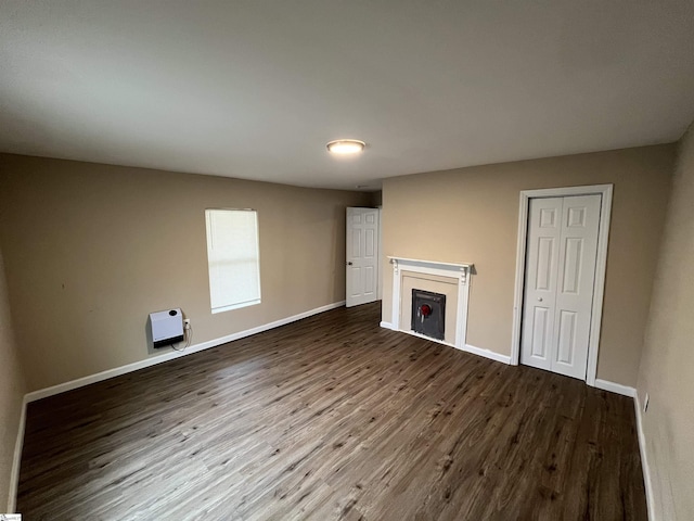 unfurnished living room with dark wood-type flooring and heating unit