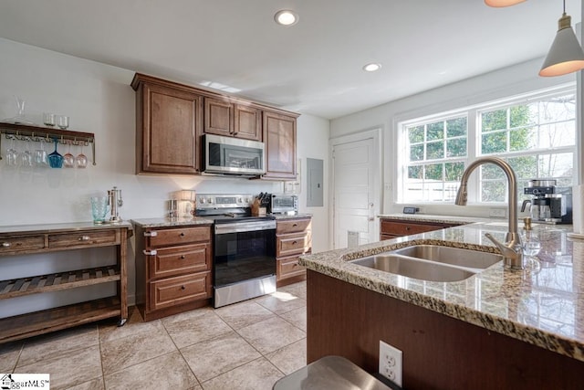 kitchen with sink, hanging light fixtures, electric panel, light stone counters, and stainless steel appliances