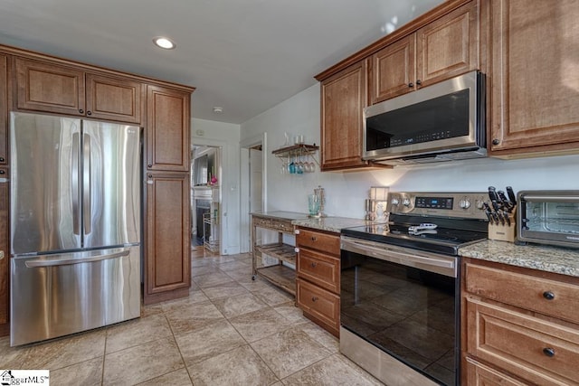 kitchen featuring light stone countertops, light tile patterned floors, and stainless steel appliances