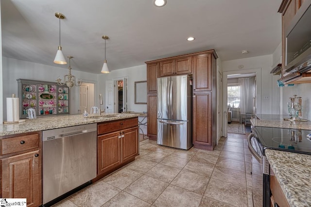 kitchen featuring sink, decorative light fixtures, stainless steel appliances, and light stone countertops