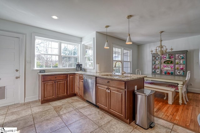 kitchen with decorative light fixtures, dishwasher, sink, kitchen peninsula, and light stone countertops