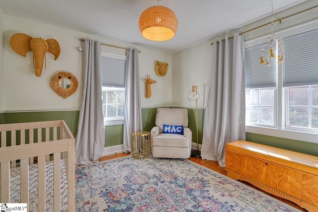 bedroom featuring wood-type flooring and a nursery area