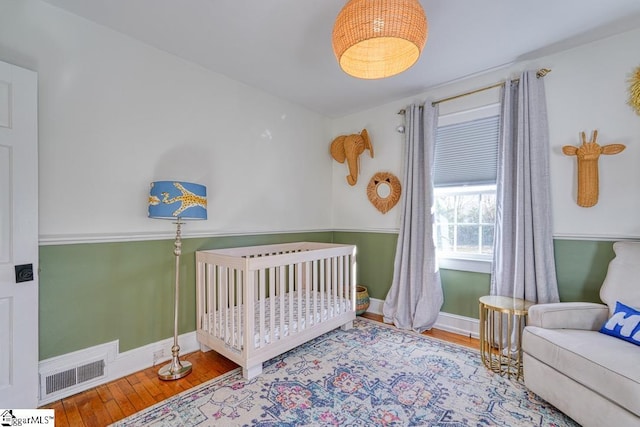 bedroom featuring a nursery area and wood-type flooring