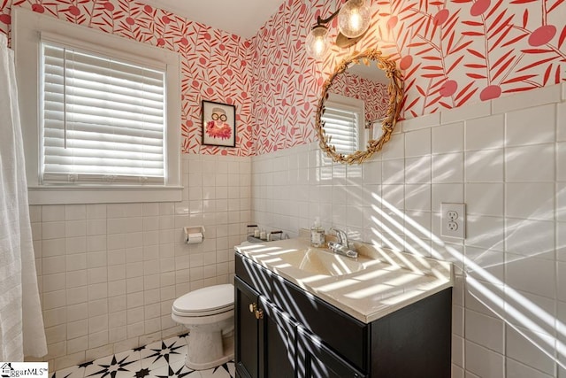 bathroom featuring vanity, tile walls, and toilet