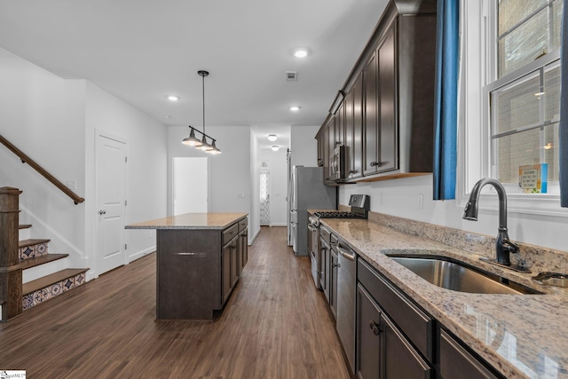 kitchen with light stone counters, sink, stainless steel appliances, and a kitchen island