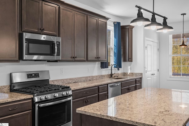 kitchen with dark brown cabinetry, sink, decorative light fixtures, and appliances with stainless steel finishes