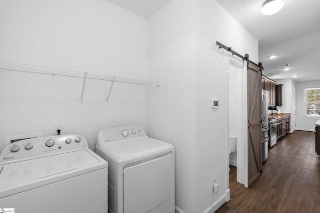 laundry area with dark hardwood / wood-style flooring, washer and clothes dryer, and a barn door