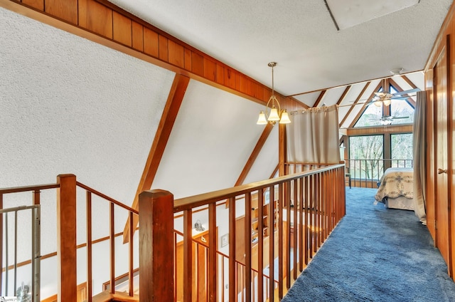 hall featuring an inviting chandelier, vaulted ceiling, a textured ceiling, and carpet