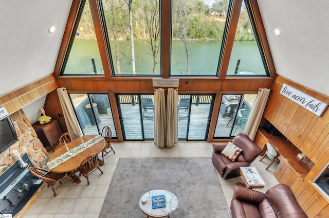 living room with a towering ceiling, light tile patterned floors, and wood walls