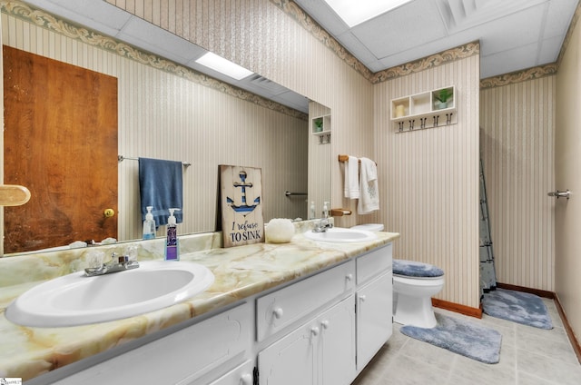 bathroom featuring vanity, toilet, tile patterned flooring, and a drop ceiling